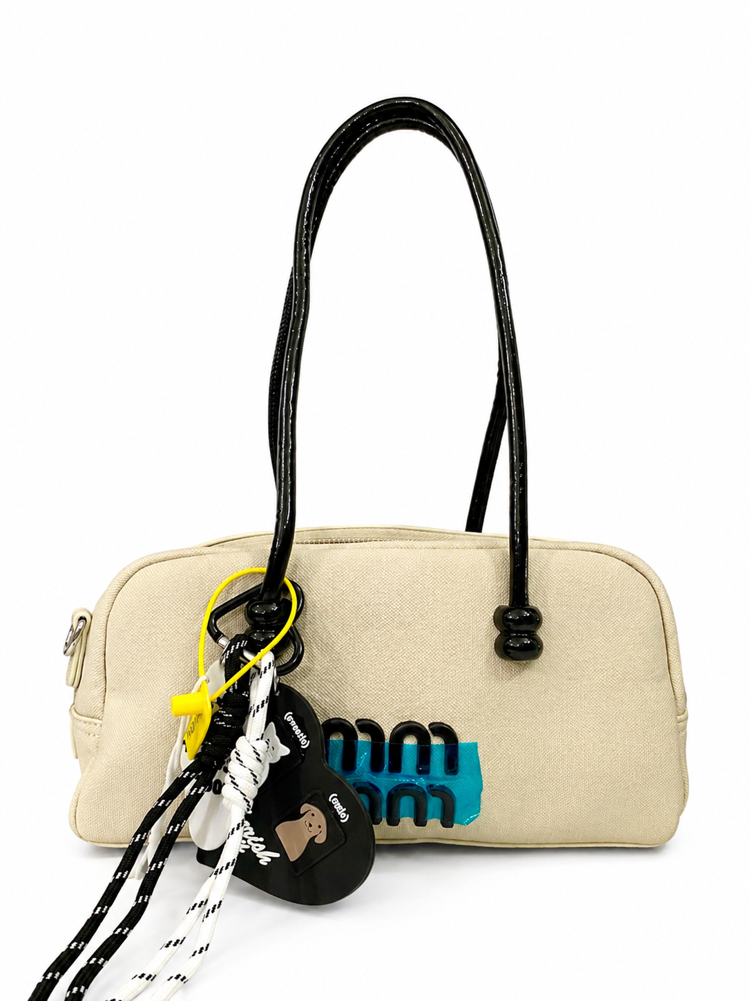 A premium Elegant Canvas Mini Handbag with Glossy Handles & Charm Accessories – Beige