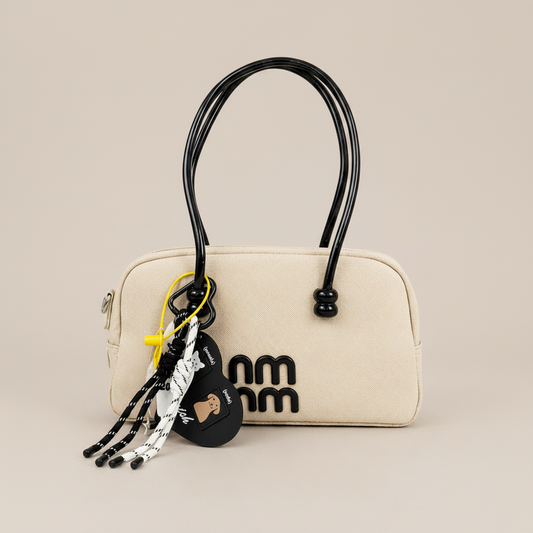 A premium Elegant Canvas Mini Handbag with Glossy Handles & Charm Accessories – Beige