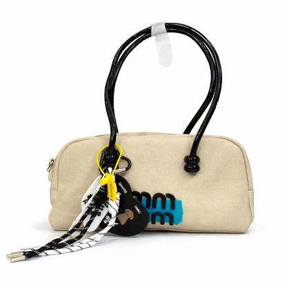 A premium Elegant Canvas Mini Handbag with Glossy Handles & Charm Accessories – Beige